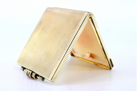 Caixa de toilette em prata dourada com relevos na tampa espelho e base para pó de arroz com aplicação de rubis caibrados na abertura.